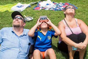 three people sitting and viewing solar eclipse